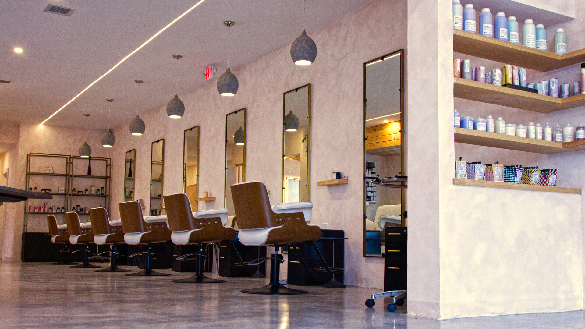 The styling floor at Red Market & Martial Vivot — a row of styling chairs along pink walls under pendant lights