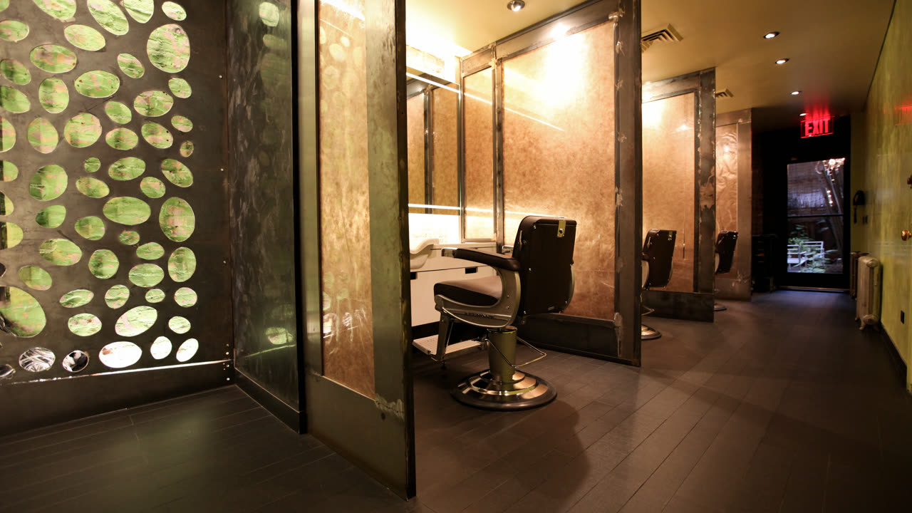 Inside the Martial Vivot flagship salon in New York — barber chairs between brass and steel partitions