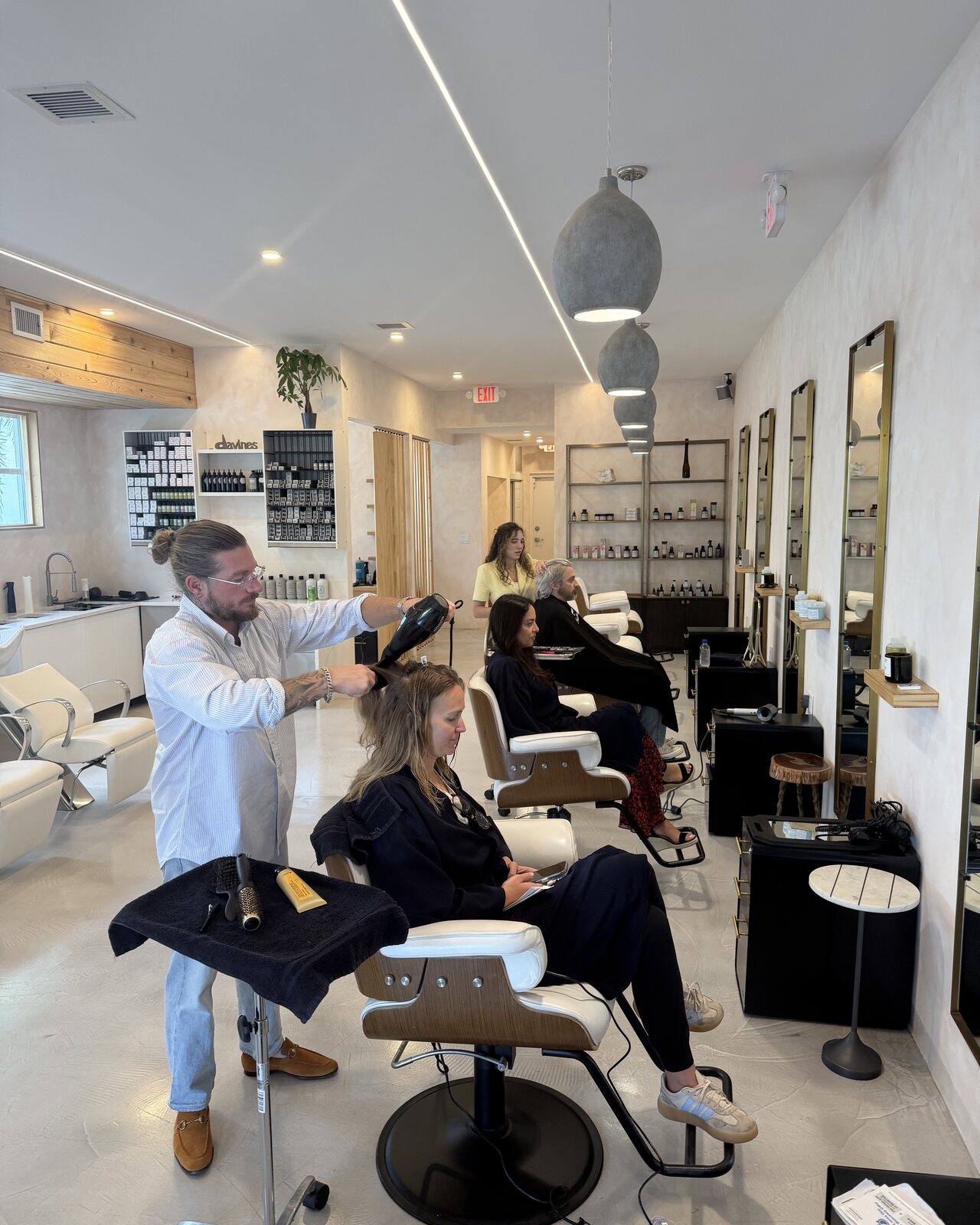 A precision haircut in progress at Red Market & Martial Vivot — Paris-trained stylist sectioning hair at a leather chair